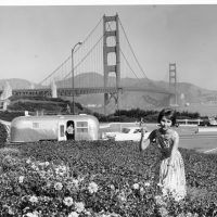Stopping to pick flowers in San Francisco in 1964, with the Golden Gate Bridge as a backdrop. The car is a 1964 Cadillac, and the trailer is an Airstream Land Yacht.