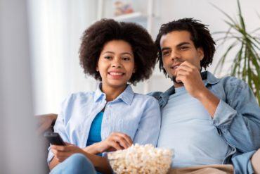 smiling couple with popcorn watching tv at home PD7QCQH