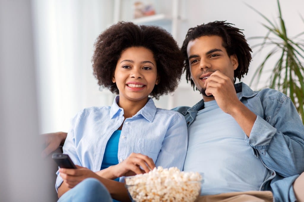 smiling couple with popcorn watching tv at home PD7QCQH