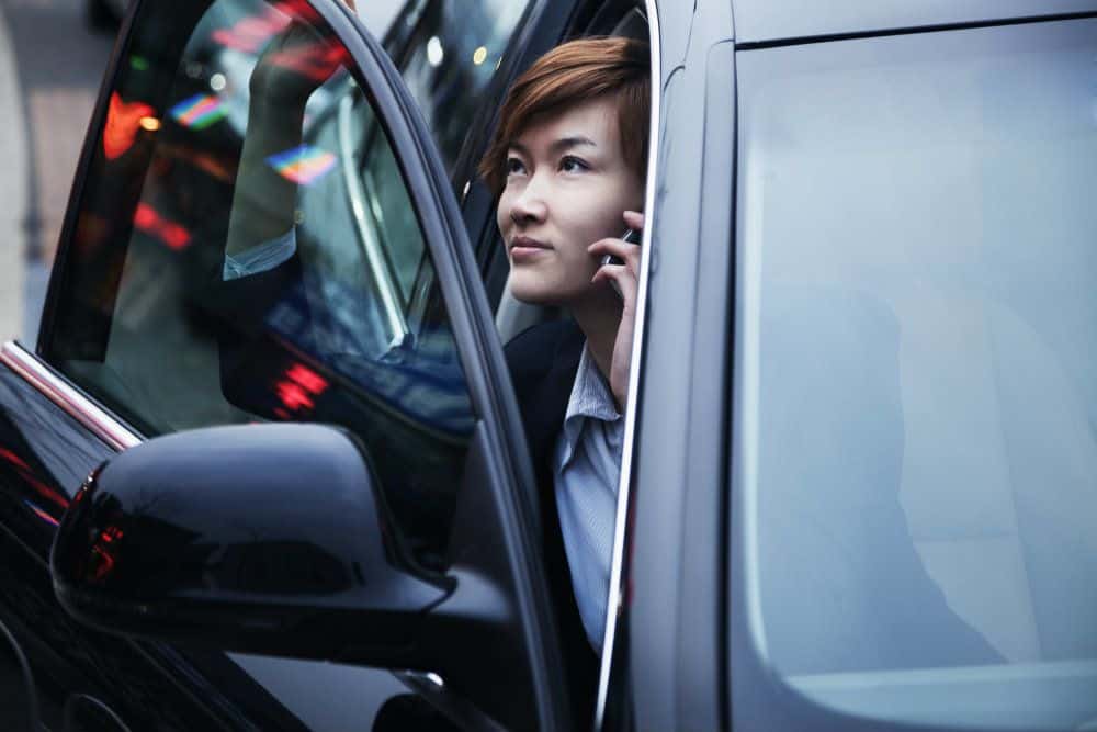 businesswoman exiting car while on the phone PWK4PCR
