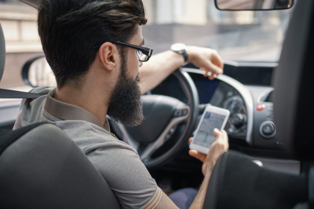 Progressive insurance reviews for its Snapshot program show that it tracks behavior like this man looking at his phone while driving a car.