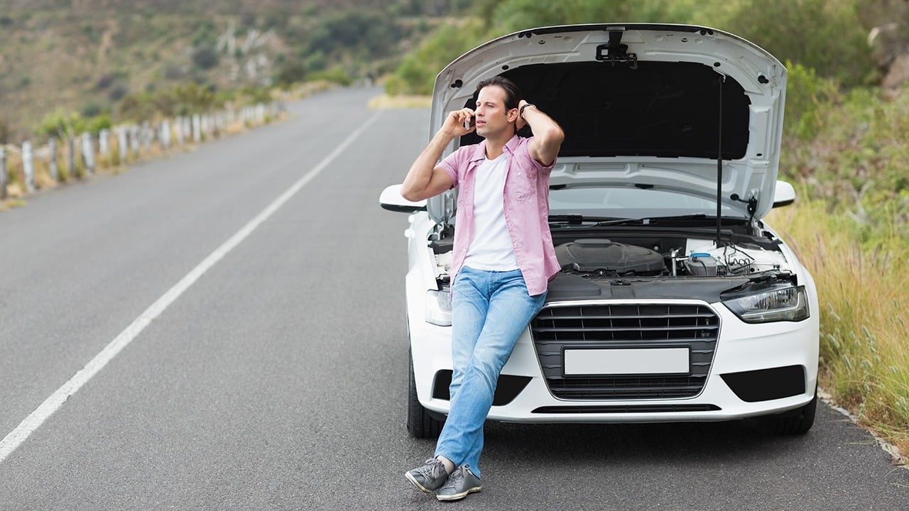 Nationwide insurance reviews mention roadside assistance to help you if you get stuck like this woman on the phone in front of a broken down white sedan.