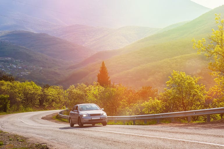 car moves on a mountain road under in the sun