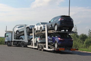 You can get car shipping quotes online to help you get your car shipped in an auto transporter that carries cars down a highway like this one pictured.