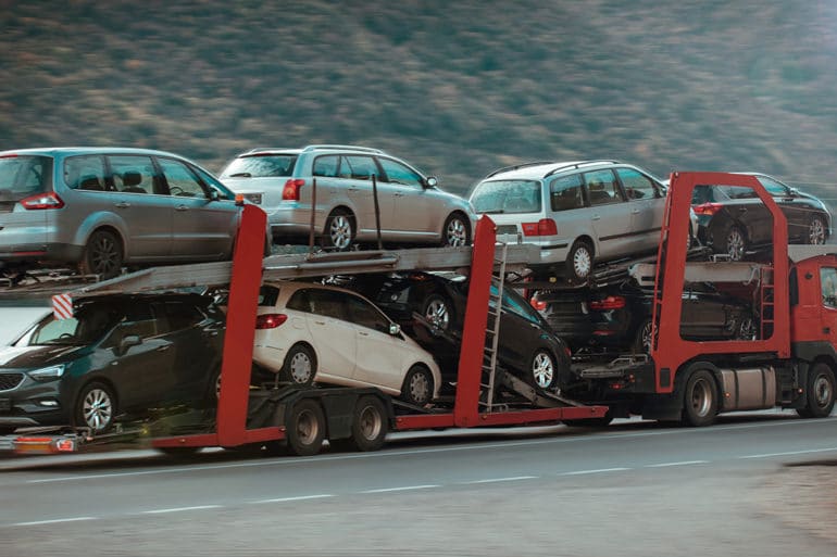 Easy Auto Ship reviews mention options like this open car carrier in motion down a highway with multiple cars on it.
