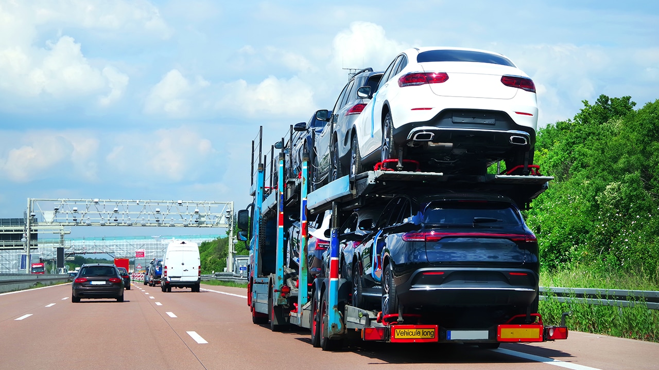 Sherpa Auto Transport reviews mention easy shipping with transport options like this open car carrier with multiple vehicles traveling down a highway.