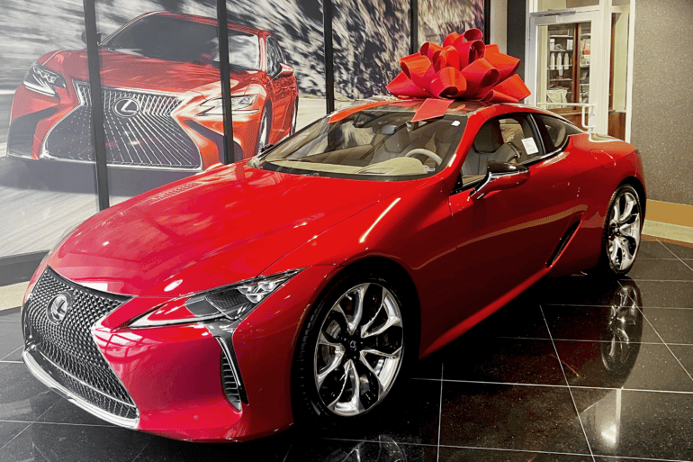 A red Lexus sitting in a showroom with a giant red bow.