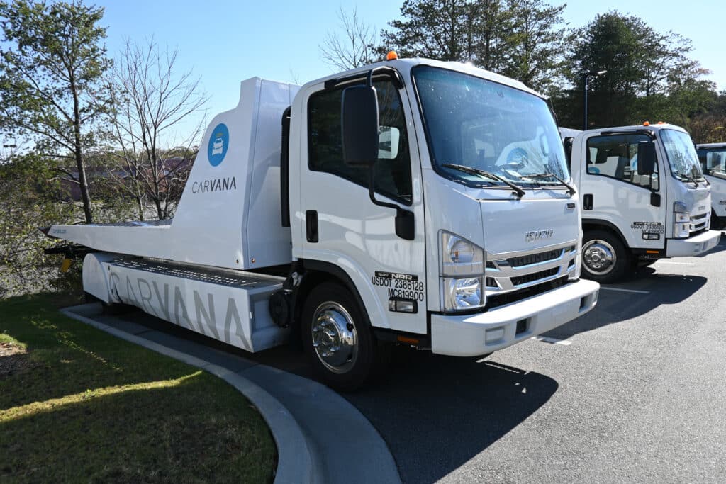 Carvana delivery trucks lined up in a parking lot.