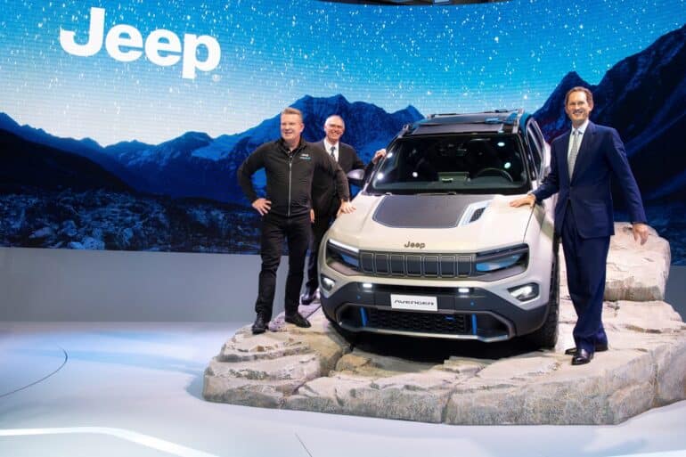 executives stand next to a new jeep ev, the avenger, on display