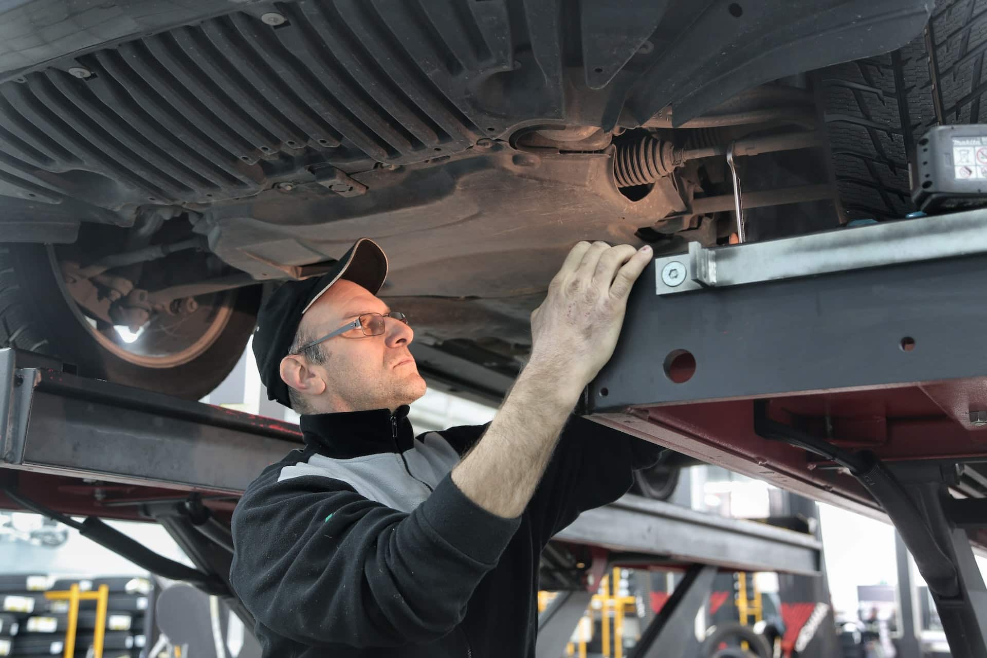 an ase certified mechanic works underneath a vehicle