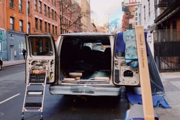 a moving van waits being packed with things on a city block