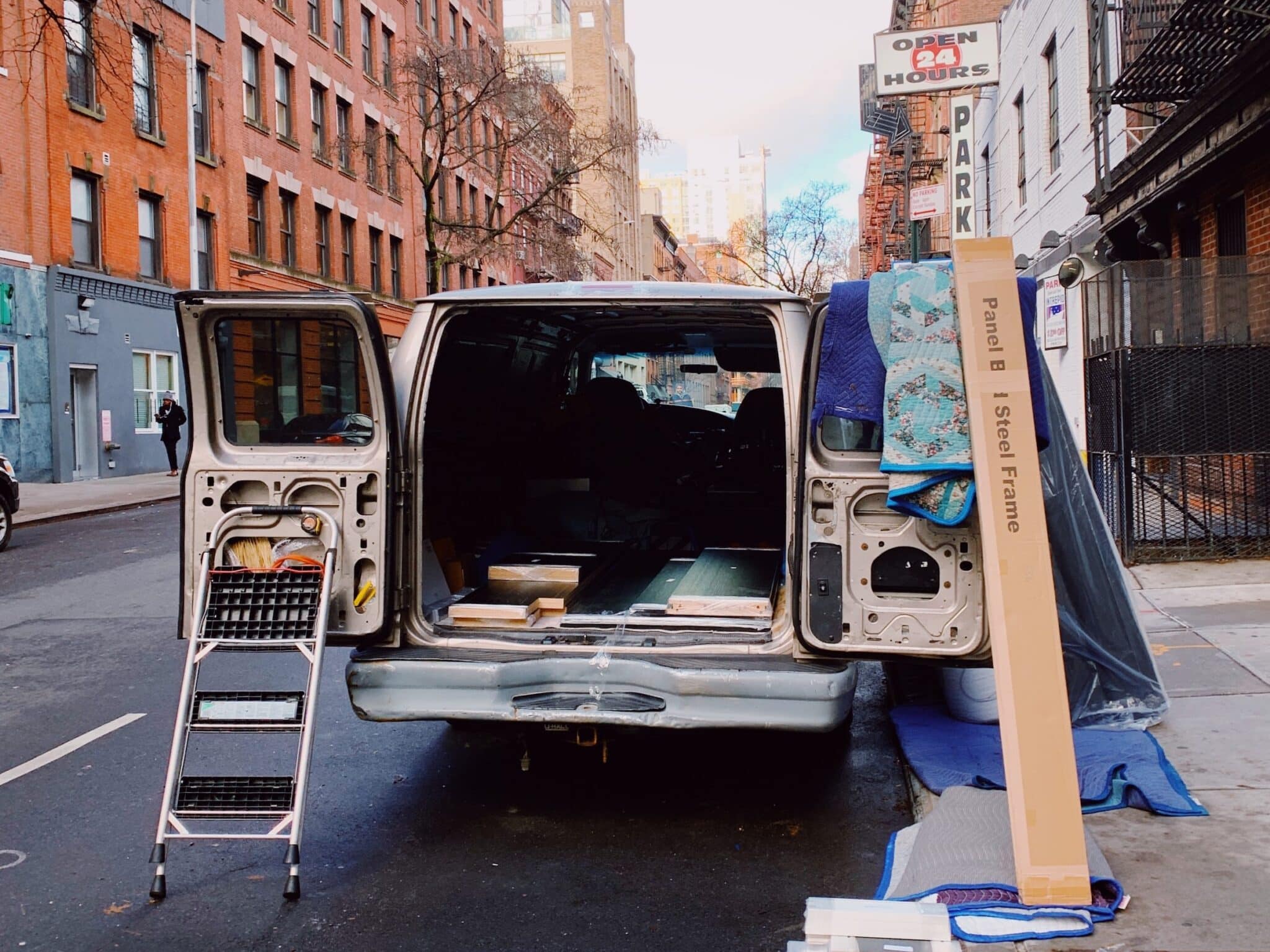 a moving van waits being packed with things on a city block