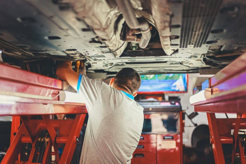 a mechanic works on a vehicle on a lift