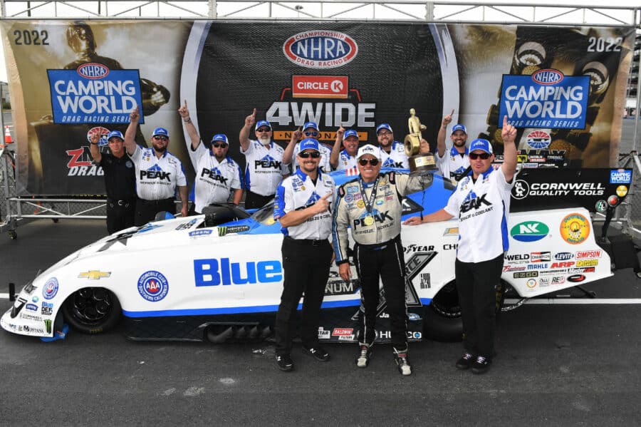 john force celebrates a victory with his team in front of his funny car